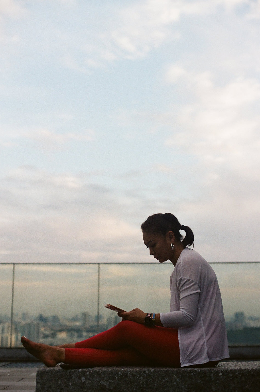 EQL x RAH leggings in Lava worn on a rooftop ledge at dusk