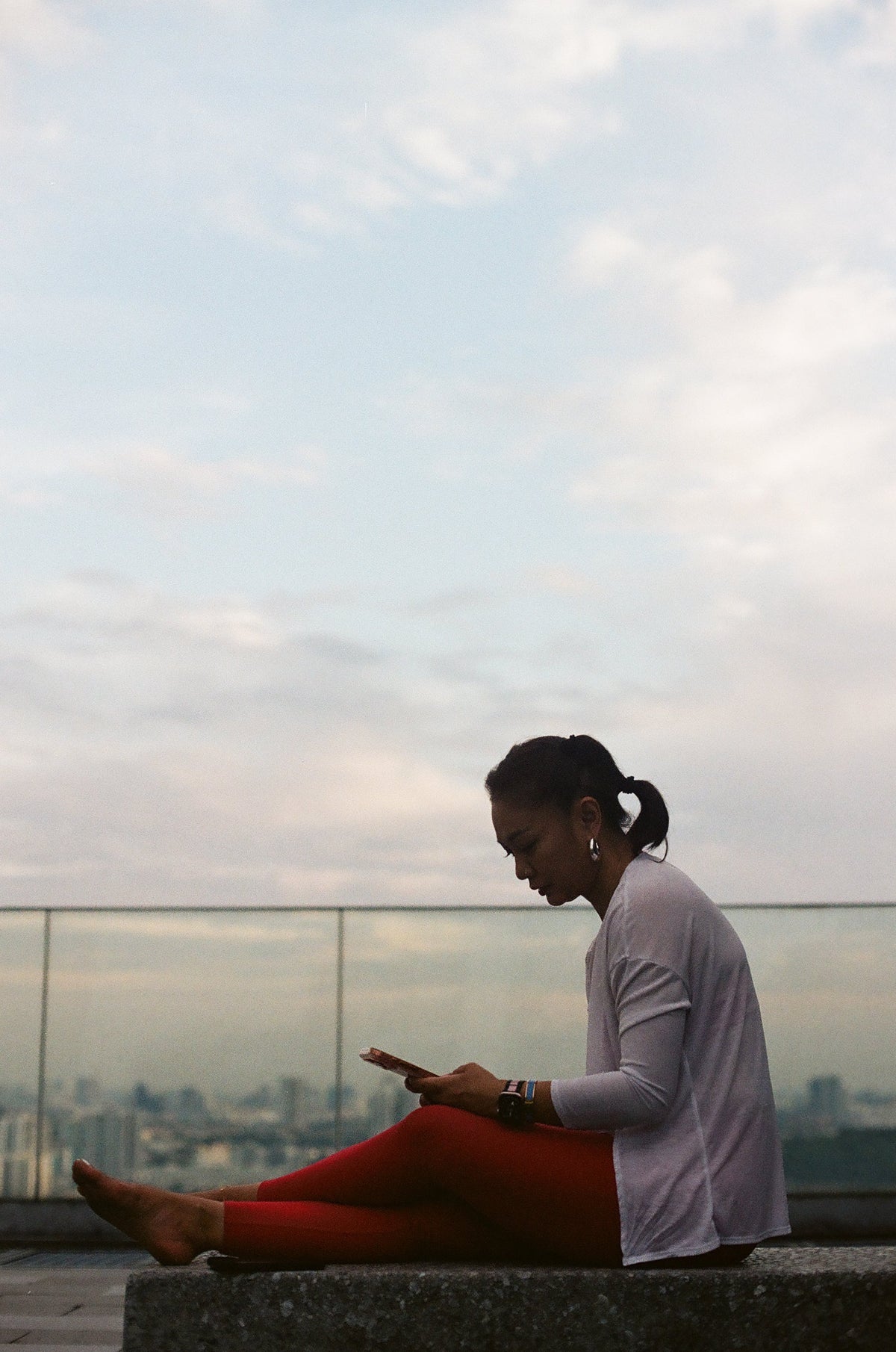EQL x RAH leggings in Lava worn on a rooftop ledge at dusk
