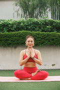 EQL x RAH high-waisted leggings in Lava, seated in lotus